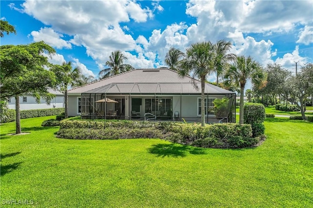 back of property featuring a lanai and a lawn