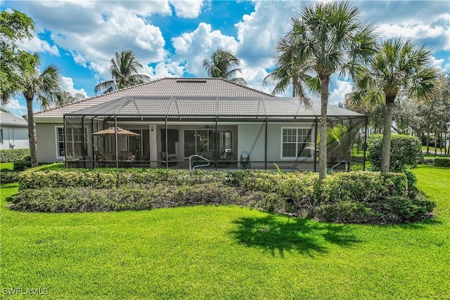 rear view of house featuring a lawn and glass enclosure