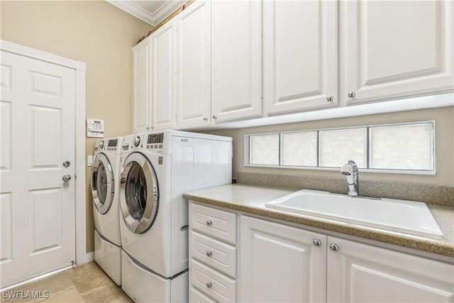 clothes washing area featuring crown molding, cabinets, independent washer and dryer, and sink