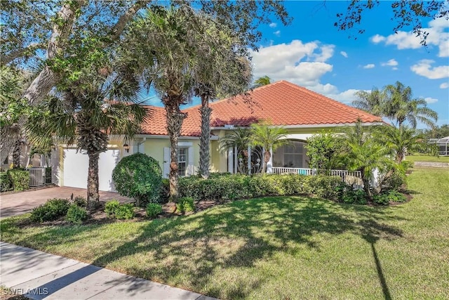 mediterranean / spanish home with a garage and a front lawn