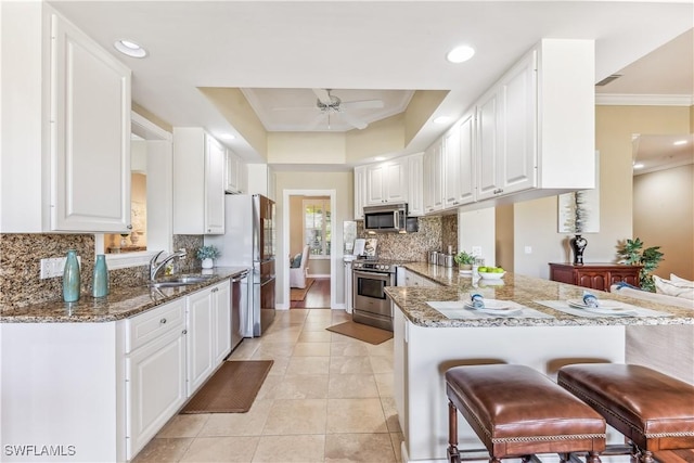 kitchen featuring kitchen peninsula, dark stone countertops, white cabinets, and appliances with stainless steel finishes