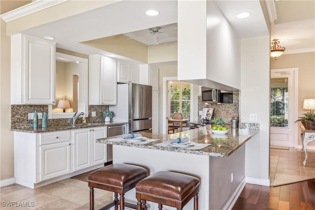 kitchen featuring kitchen peninsula, light wood-type flooring, white cabinets, and a healthy amount of sunlight