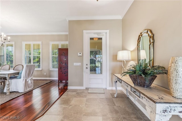 entrance foyer featuring an inviting chandelier, ornamental molding, and light wood-type flooring