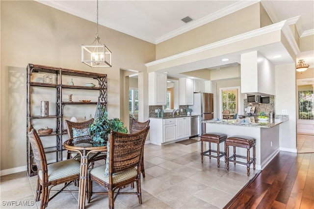 dining area featuring an inviting chandelier, light hardwood / wood-style floors, crown molding, and a healthy amount of sunlight