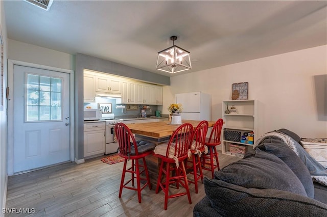 dining space with visible vents, a notable chandelier, and light wood finished floors