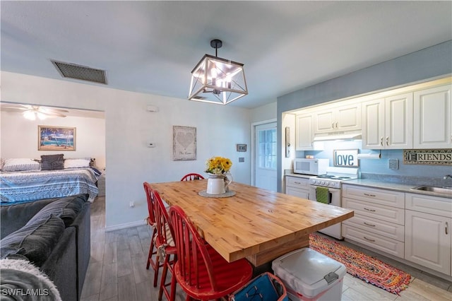 dining room with a notable chandelier, wood finished floors, visible vents, and baseboards