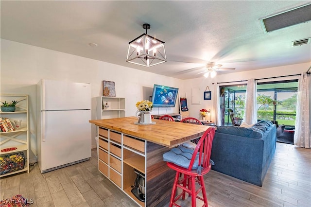 kitchen featuring visible vents, butcher block counters, freestanding refrigerator, and light wood-style floors