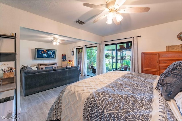 bedroom with a ceiling fan, access to outside, visible vents, and wood finished floors