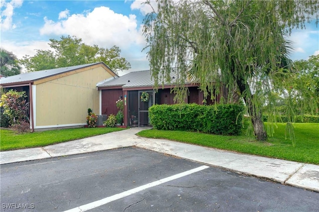 view of front of home featuring uncovered parking, metal roof, and a front yard