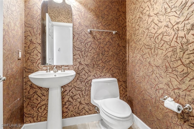 bathroom with tile patterned floors, toilet, wallpapered walls, and baseboards