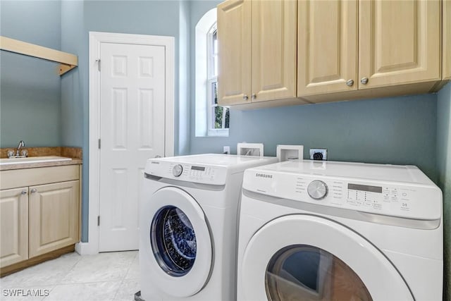 laundry room featuring cabinet space, light tile patterned floors, washing machine and dryer, and a sink