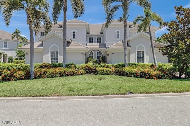 mediterranean / spanish-style home featuring stucco siding, a front lawn, and a tiled roof