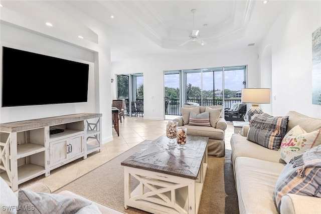 tiled living room with a tray ceiling, ceiling fan, and ornamental molding