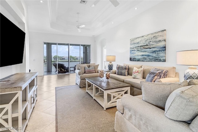 living area featuring light tile patterned floors, a tray ceiling, arched walkways, ceiling fan, and a towering ceiling