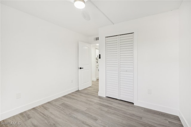 unfurnished bedroom with light hardwood / wood-style floors, ceiling fan, and a closet