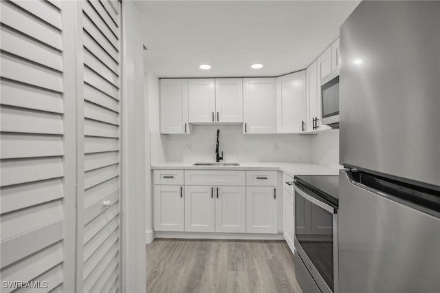 kitchen with white cabinetry, light hardwood / wood-style flooring, stainless steel appliances, and sink