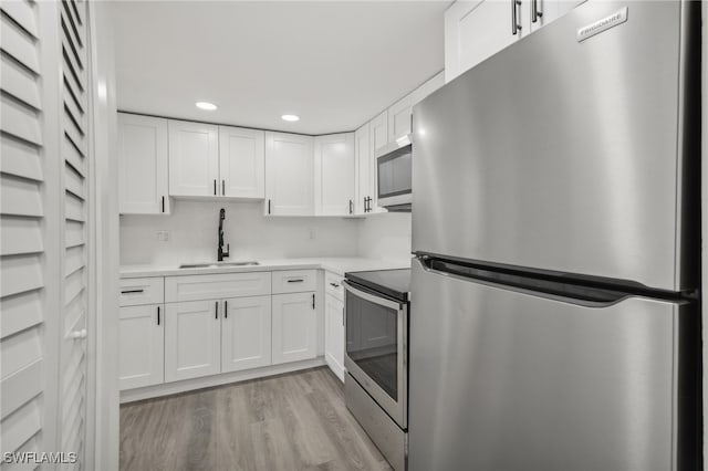 kitchen with light hardwood / wood-style flooring, white cabinets, appliances with stainless steel finishes, and sink