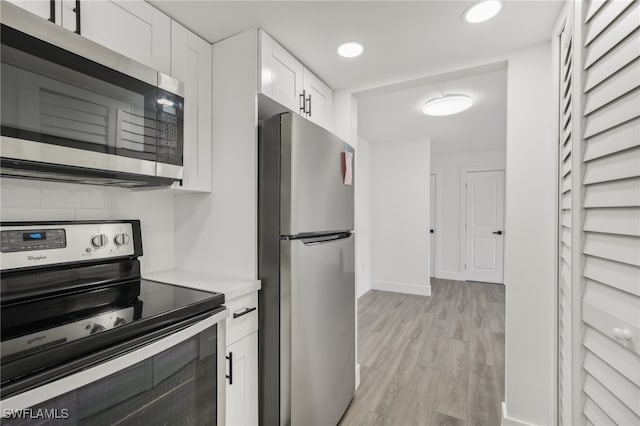 kitchen with white cabinetry, light hardwood / wood-style flooring, backsplash, and stainless steel appliances