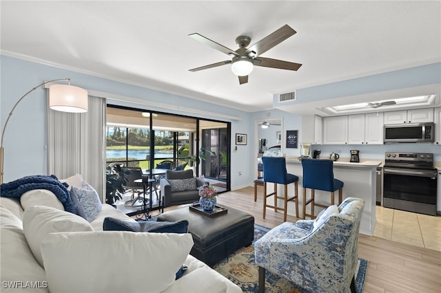 living room with crown molding, ceiling fan, and light hardwood / wood-style flooring