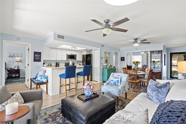 living room featuring crown molding, ceiling fan, and light hardwood / wood-style flooring