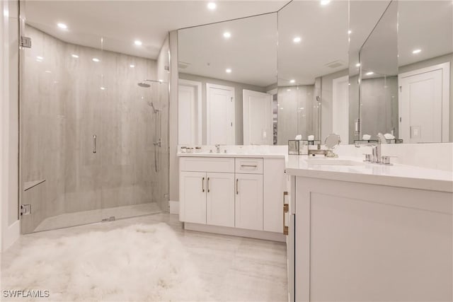 full bath featuring recessed lighting, two vanities, a sink, and a marble finish shower