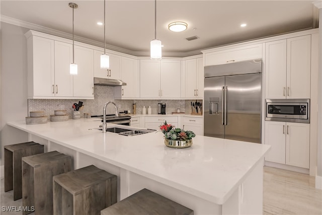 kitchen featuring white cabinets, kitchen peninsula, built in appliances, a kitchen breakfast bar, and pendant lighting