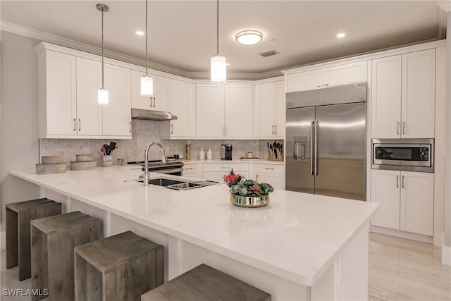 kitchen featuring built in appliances, a peninsula, a breakfast bar, and under cabinet range hood