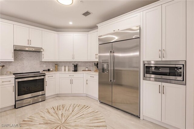 kitchen with built in appliances, backsplash, and white cabinetry