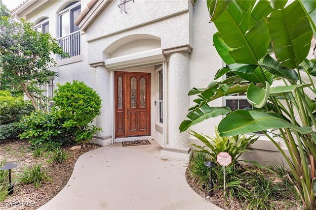 entrance to property featuring a balcony and stucco siding