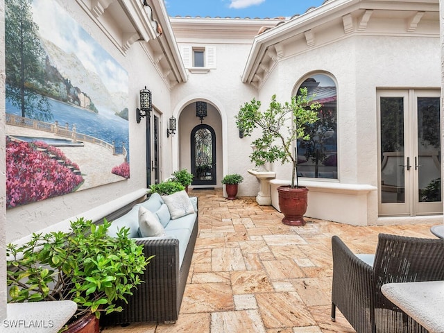 doorway to property featuring french doors, an outdoor living space, and a patio area