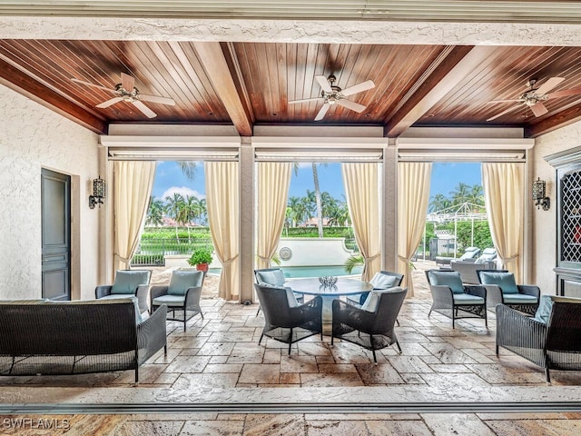 sunroom with ceiling fan, wooden ceiling, and beamed ceiling