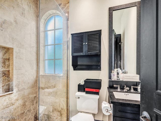 bathroom featuring tiled shower, plenty of natural light, toilet, and vanity