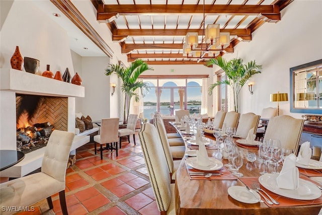 dining room with beamed ceiling, a water view, a premium fireplace, and a notable chandelier