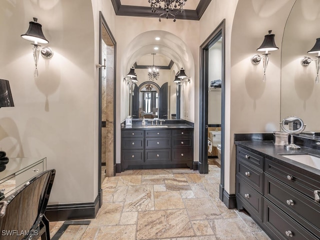 bathroom with ornamental molding, vanity, an inviting chandelier, and toilet