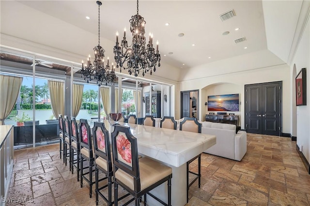 18281 Via Caprini Dr, Miromar Lakes, FL 33913 - dining area with stone tile floors, a chandelier, recessed lighting, arched walkways, and a high ceiling