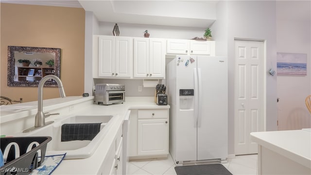 kitchen featuring white refrigerator with ice dispenser, sink, white cabinets, and light tile patterned flooring