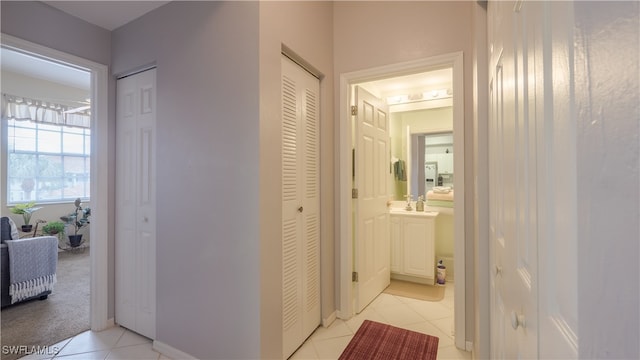 hall featuring light tile patterned flooring and sink