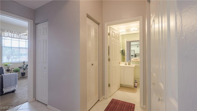 hallway featuring a sink, light carpet, and light tile patterned flooring