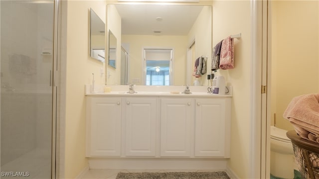 bathroom with tile patterned floors, a shower with shower door, toilet, and vanity