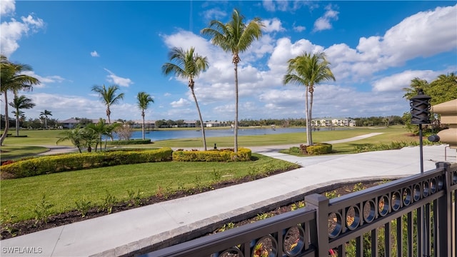 surrounding community with a water view and a lawn