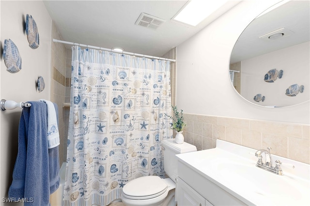 bathroom featuring vanity, toilet, tile walls, and tasteful backsplash