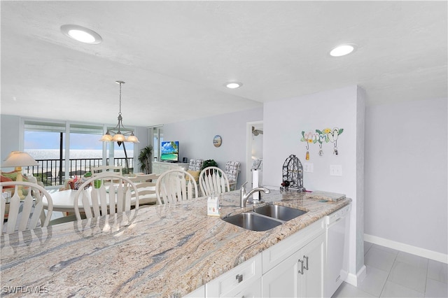 kitchen featuring light stone countertops, white dishwasher, sink, a chandelier, and white cabinetry