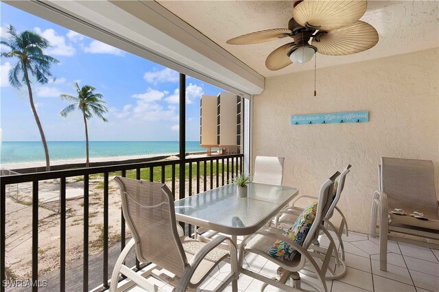 balcony featuring a beach view, a water view, and ceiling fan