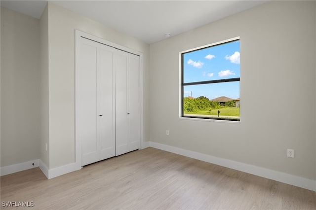 unfurnished bedroom featuring light wood-type flooring and a closet