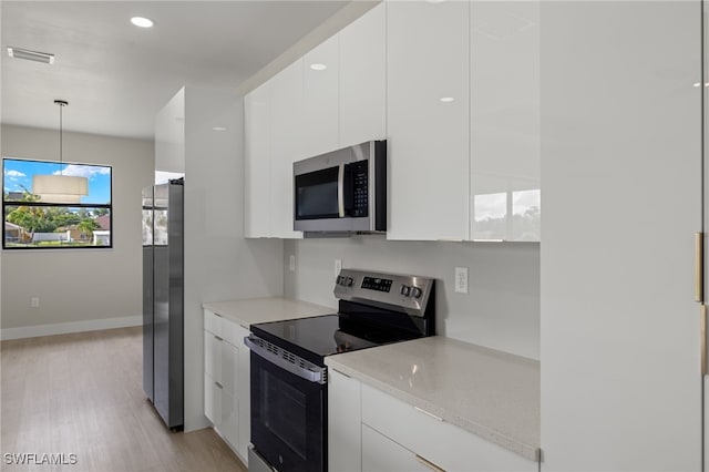 kitchen with white cabinets, light stone countertops, stainless steel appliances, and light hardwood / wood-style flooring