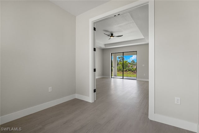 unfurnished room featuring a raised ceiling, light hardwood / wood-style flooring, and ceiling fan