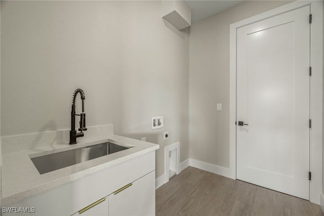 clothes washing area with hookup for a washing machine, light wood-type flooring, electric dryer hookup, sink, and cabinets