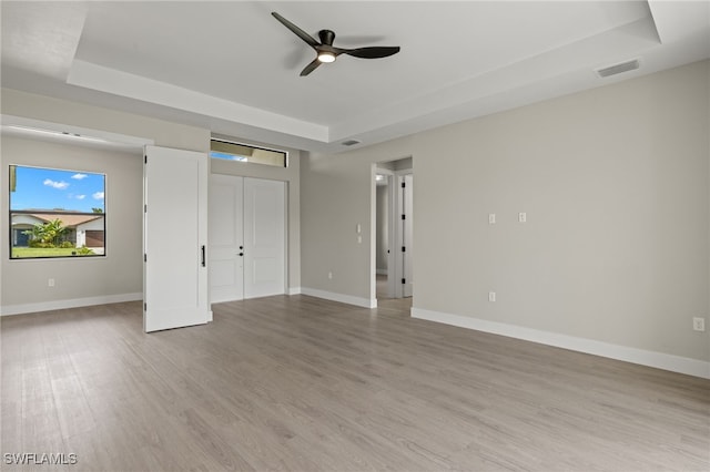 unfurnished bedroom with a raised ceiling, ceiling fan, and hardwood / wood-style floors