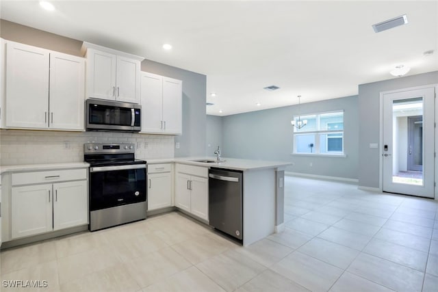 kitchen with white cabinetry, hanging light fixtures, stainless steel appliances, tasteful backsplash, and kitchen peninsula