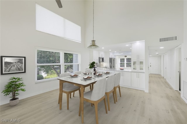 dining room featuring light wood-type flooring and a high ceiling